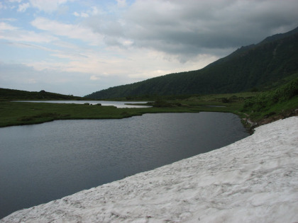 残雪の池塘のフチを歩きます