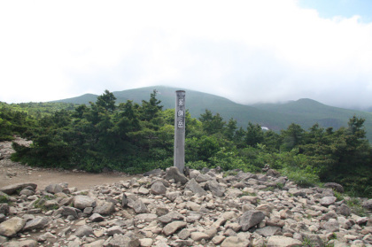 なだらかな平地にぽつんと立つ薬師岳の標識。