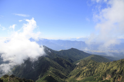 赤岳の山頂から見た八ヶ岳の南の尾根。権現岳や西岳が見えます。背景には雲に見え隠れしている南アルプスがあります。