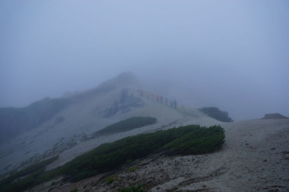 燕岳の行列。霧をすかして赤青黄色の雨合羽が見えます。