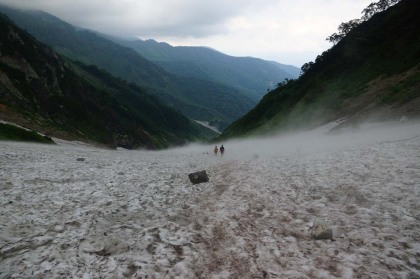 下山する登山者。雪渓の上の踏み跡は一人が通れるだけの幅しかないので、原則の通りに登る人が脇に避けてすれ違います。