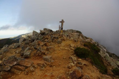 鷲羽岳の山頂。霧がかかったり晴れたり、強い東風が吹き抜けています。