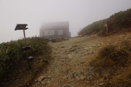 谷川岳肩ノ小屋。霧が深い上に、横殴りの風が吹き始めました。