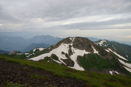 白馬岳の西にそびえる旭岳。残雪を踏んでいる登山道は山頂を巻いて祖母谷温泉に下っています。