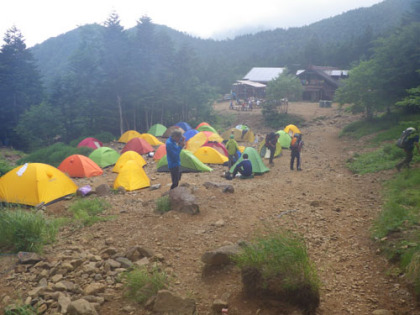 行者小屋のテント場。奥に山小屋が見えます。