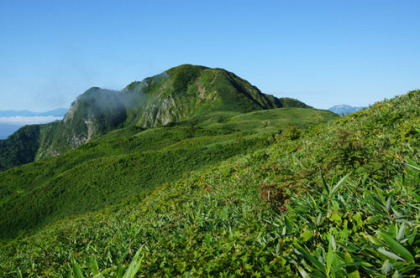 笹平越しに見た雨飾山の山頂。