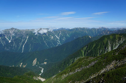 北アルプスの連嶺。左端が笠ヶ岳。双六岳、三俣蓮華岳、鷲羽岳、水晶岳の四座は重なって見える。水晶岳が最も高く背後に黒い山容を見せている。間にある赤茶けた大きな山塊が薬師岳。